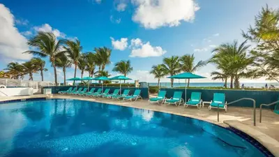 a swimming pool with blue chairs and umbrellas at Deluxe Studio Balcony Bay View Amazing Pool in Sunny Isles Beach