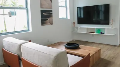 a living room with a tv and a table and chairs at Beach Haus Design District in Miami