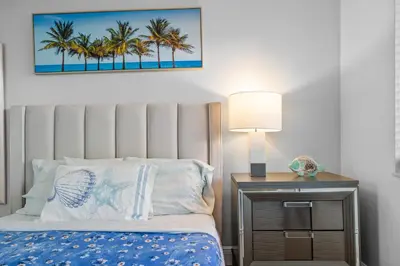 a bedroom with a bed with a lamp and palm trees at Riverbend Apartments by Lowkl in Fort Lauderdale