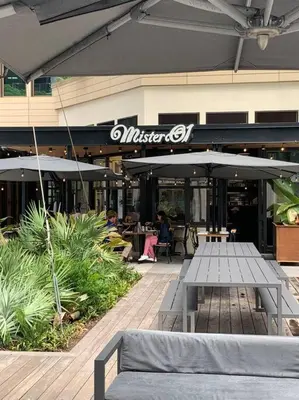 a restaurant with a bench and tables and umbrellas at GroveO5 10 minutes from Miami Beach in Miami