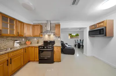 a kitchen with wooden cabinets and a stove at Casa Neisy Florida 10 minutes from Hollywood Beach and Hard Rock Hotel & Casino Hollywood in Hollywood