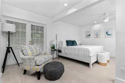 a white bedroom with a bed and a chair at The Riverside Retreat 1 in Fort Lauderdale