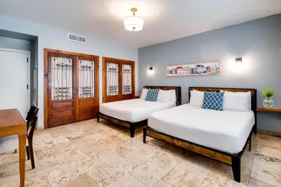 two beds in a room with a table and a desk at Kasa La Flora And Impala Miami Beach in Miami Beach