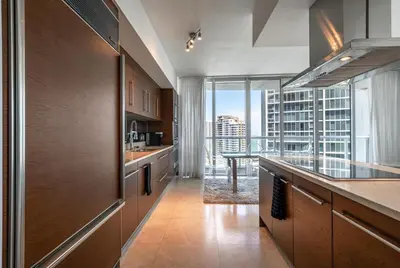 a kitchen with wooden cabinets and a large window at ICON Brickell Miami- 2 bedroom Condo with City and water views! in Miami