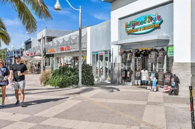 a man and woman walking down a street in front of shops at Beachfront & Pool Near Marriott Hollywood Beach in Hollywood