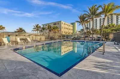 a swimming pool with palm trees and a building at Beachfront & Pool Access Unit W 2 Queen Beds in Hollywood