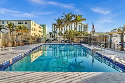 a swimming pool at a resort with palm trees and buildings at Beachfront & Pool Access Unit W 2 Queen Beds in Hollywood