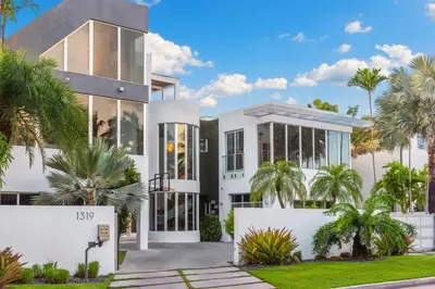 a white house with palm trees in front of it at Villa Seminole in Fort Lauderdale