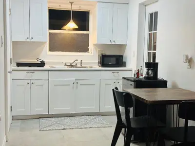a kitchen with white cabinets and a wooden table at Wilton Manors Guesthouse in Fort Lauderdale