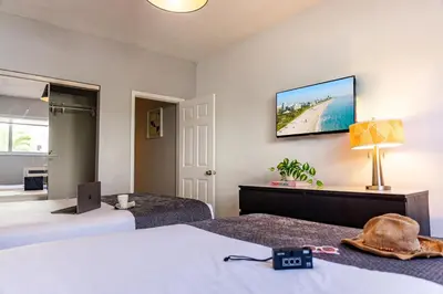 a hotel room with two beds and a laptop on the wall at Beachside All Suites Hotel in Miami Beach