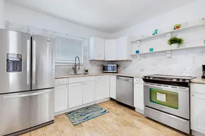 a kitchen with white cabinets and stainless steel appliances at ULTRA chic apartment steps from the beach in Hollywood