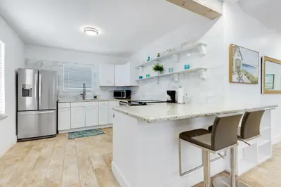 a white kitchen with a counter and a refrigerator at ULTRA chic apartment steps from the beach in Hollywood