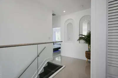 a hallway with white walls and a staircase with a potted plant at LuxOasis Getaway Minigolf, Pool, Beach, Chess, Jacuzzi in Tamiami