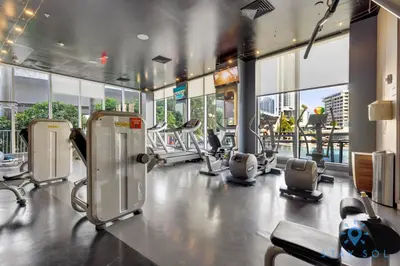 a gym with cardio equipment in a building with windows at Infinite View Balcony Pool Near Beach in Hallandale Beach