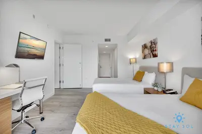 a hotel room with two beds and a desk at Infinite View Balcony Pool Near Beach in Hallandale Beach