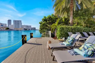 a row of lounge chairs next to a body of water at Infinite View Balcony Pool Near Beach in Hallandale Beach