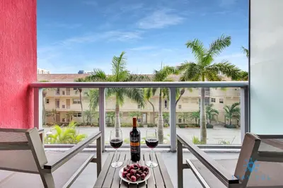a table with two glasses of wine on a balcony at Infinite View Balcony Pool Near Beach in Hallandale Beach