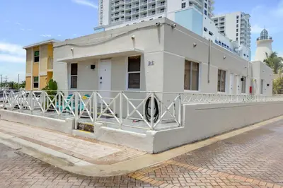 a white building with a fence on a street at ULTRA Modern Apartment by the Beach in Hollywood