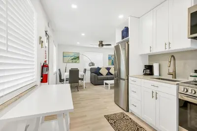 a kitchen and living room with white cabinets at ULTRA spacious apartment steps from the beach in Hollywood
