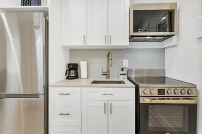 a kitchen with white cabinets and a stainless steel refrigerator at ULTRA exciting apartment at the Boardwalk in Hollywood