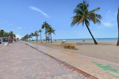 a brick road next to a beach with palm trees at ULTRA exciting apartment at the Boardwalk in Hollywood