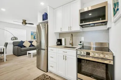a kitchen with white cabinets and a stainless steel refrigerator at ULTRA exciting apartment at the Boardwalk in Hollywood