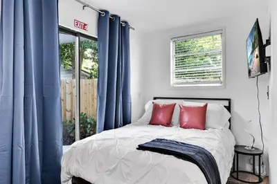 a bedroom with blue curtains and a bed with red pillows at Ventur Tropical with Elite Pool & Ultimate Fun Zone in Fort Lauderdale