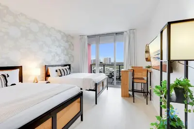 a hotel room with two beds and a desk and a balcony at Amazing Studio Infinity View Balcony in Hallandale Beach