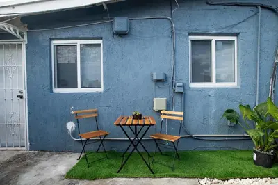 two chairs and a table in front of a blue house at The Myrlande Dinvil Guest Suite in North Miami Beach