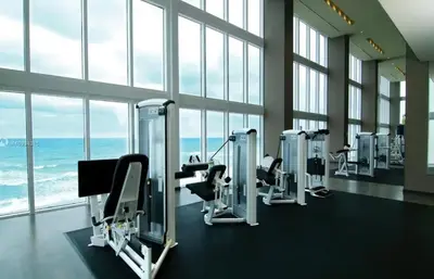 a gym with a row of tread machines in front of the ocean at Luxury High Resort Beautiful Views & Amenities in Hallandale Beach