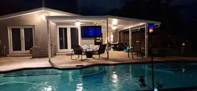 a swimming pool at night with a house with a tv at Pool House Resort heated swimming pool private duplex in Cutler Bay
