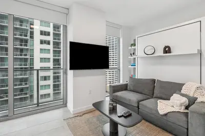 a living room with a couch and a flat screen tv at NEW Luxury Downtown Apartment - Gym Pool Workspace in Miami