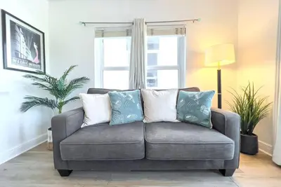 a couch with pillows in a living room with a window at Ocean Drive apartment w Balcony Walk to the Beach in Miami Beach