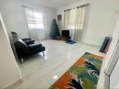 a living room with a chair and a christmas tree at Bright & Cozy Family Home Near Dania Beach in Dania Beach