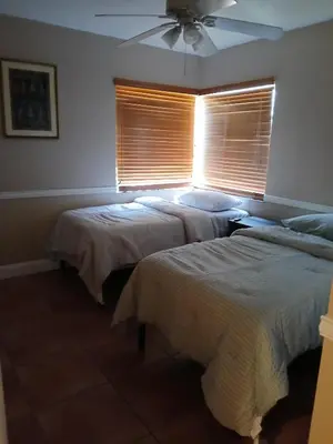 a bedroom with two beds and a window with blinds at Beautiful Miami Home in Miami