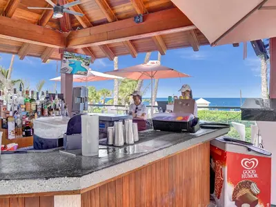 a woman sitting at a bar with an umbrella at Cozy Oceanfront Beach Service 917 in Miami Beach