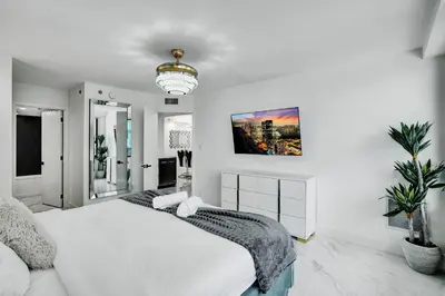 a white bedroom with a large bed and a chandelier at Ocean View Condo Beach Service 808 in Miami Beach