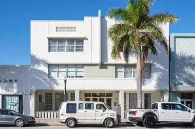 two white vehicles parked in front of a building with a palm tree at 1Bedroom Collins 2 Blocks to Ocean with Paid Street Parking in Miami Beach