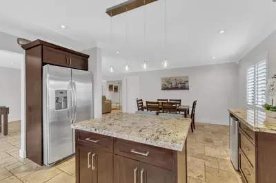 a kitchen with a stainless steel refrigerator and a table at Tropical Oasis with Heated Pool and BBQ in Tamiami