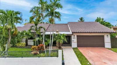 a house with palm trees in front of it at Tropical Oasis with Heated Pool and BBQ in Tamiami