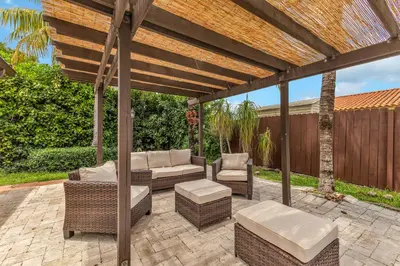 a patio with wicker furniture under a wooden pergola at Tropical Oasis with Heated Pool and BBQ in Tamiami