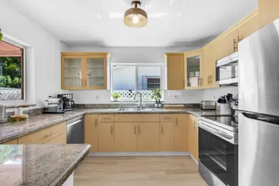 a kitchen with wooden cabinets and stainless steel appliances at Modern 3 Bedroom GetAway with Parking in Coral Gables in Miami