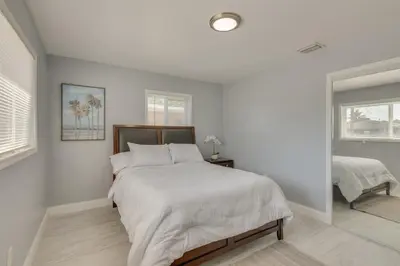 a white bedroom with a large bed and a window at Miami Gardens Apt 5 Miles to Hard Rock Stadium in Miami Gardens