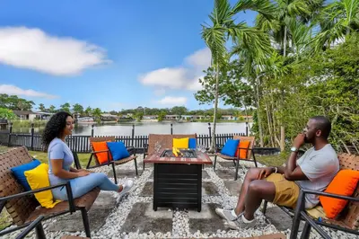 a man and woman sitting on chairs in front of a lake at Lakefront Retreat Perfect for Family Fun in Miami