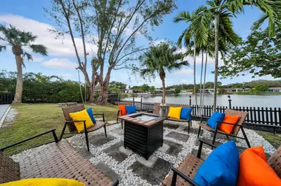 a patio with chairs and a grill next to the water at Lakefront Retreat Perfect for Family Fun in Miami