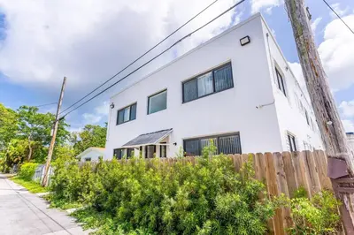 a white house with a wooden fence at Magical bright Apt 5min walking Design District apt 5 in Miami
