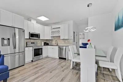 a kitchen with white cabinets and a table and chairs at Magical bright Apt 5min walking Design District apt 5 in Miami