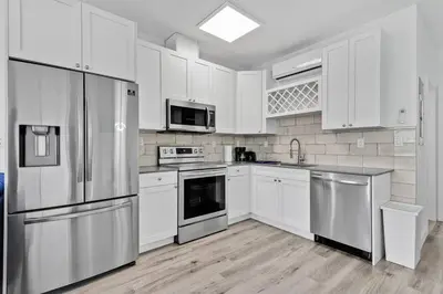 a kitchen with white cabinets and stainless steel appliances at Magical bright Apt 5min walking Design District apt 5 in Miami