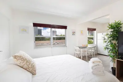 a white bedroom with a large bed and a table at B06 5 min from beach studio Midtown in Miami