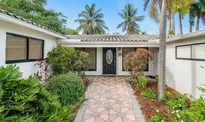 a house with palm trees in front of it at Charming 2BR Waterfront House in Fort Lauderdale